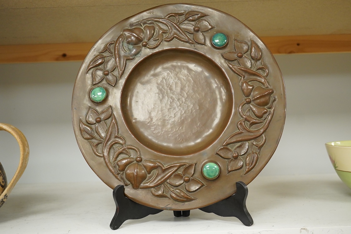 An Arts and Crafts embossed floral dish, in the manner of John Pearson, inlaid with Ruskin cabochons, unsigned, 32cm in diameter